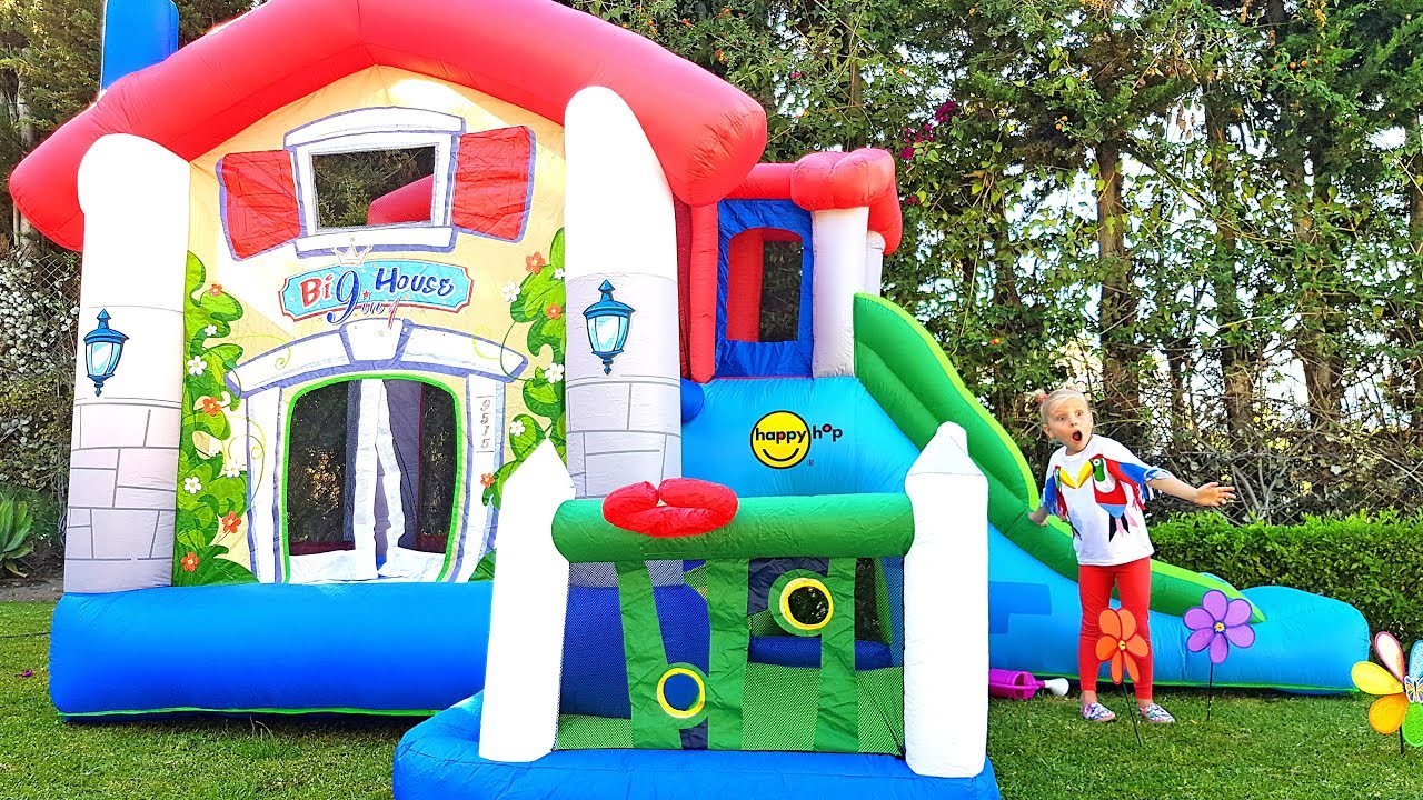 Hermanas divertidas juegan Con una gran casa de juegos inflable y nuevos juguetes